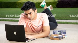 
									Emotions , a boy , laying down , casual outfit , thinking ,  posing , laptop , books , legs crossed , working , studying , looking at laptop 