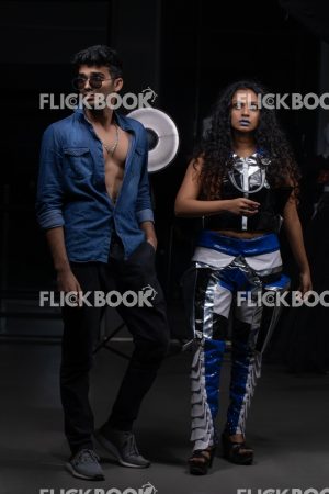 
									Fashion Design, a couple pic , A girl with blue lipstick , dark girl , curly hair , staring , posing , upward eyebrows , straight nose , facial expressions , dark skin , confident , standing , fashionable outfit , wearing a jean jacket , casual outfit , looking over sunglass
