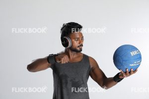 Fitness , holding a ball , wearing a headset , staring at ball , looking at ball , dark guy , wearing a skinny , sporty , well built body 