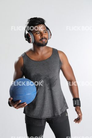 Fitness , holding a ball , wearing a headset , dark guy , wearing a skinny , sporty , well built body , looking somewhere , 