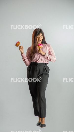 Food , A girl , holding two donuts from her fingers , smiling , office wear , standing , looking at donuts,