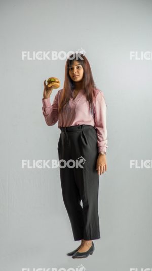 Food , A girl , holding a burger , smiling , office wear , standing , staring , posing 