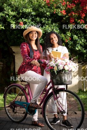 
									Entertainment,  A Two girls with a flower bicycle , at a garden , wearing a hat , casual outfit , smiling , happy 