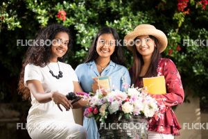 Entertainment, Three girls with a flower bicycle , at a garden , wearing a hat , casual outfit , smiling , happy 