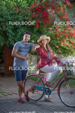 
									Entertainment, A couple with a flower bicycle , at a garden , wearing a hat , casual outfit , smiling , happy , , guy hand on girls shoulder , rose in mouth 